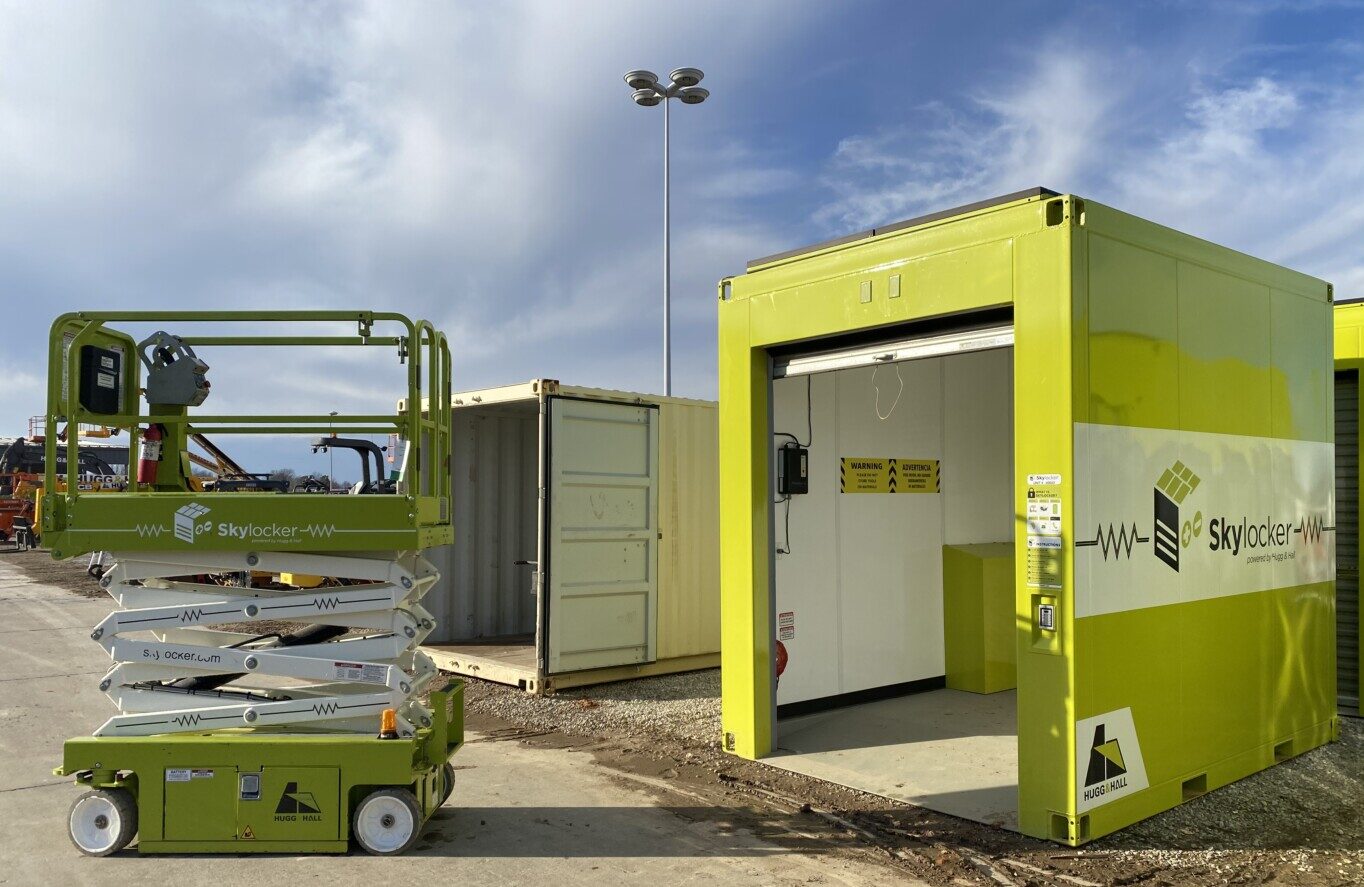 Image of Skylocker and scissor lift. Skylocker is a green equipment locker with a roll-up door in front to access the equipment. 