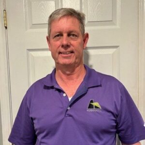 Stephen Messonnier smiles while wearing an LSU-purple Hugg & Hall polo. 