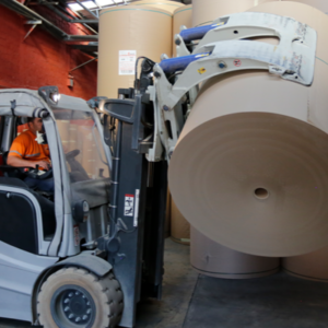 A paper roll being lifted by a clamp forklift attachment