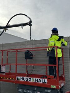 Kat Seale, female Technical Project Manager with Alquist, watches a 3d concrete printer from a Hugg & Hall scissor lift rental