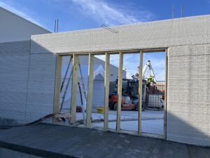 A Hugg & Hall forklift visible through an doorway in the 3D concrete printed wall. 